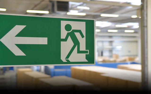 A photo of an emergency exit sign as an example of warehouse safety signs