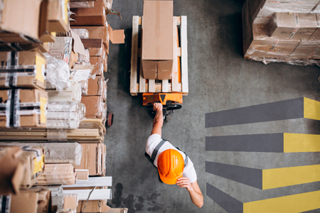 Man moving package through logistics centre to illustrate article on warehouse floor labels